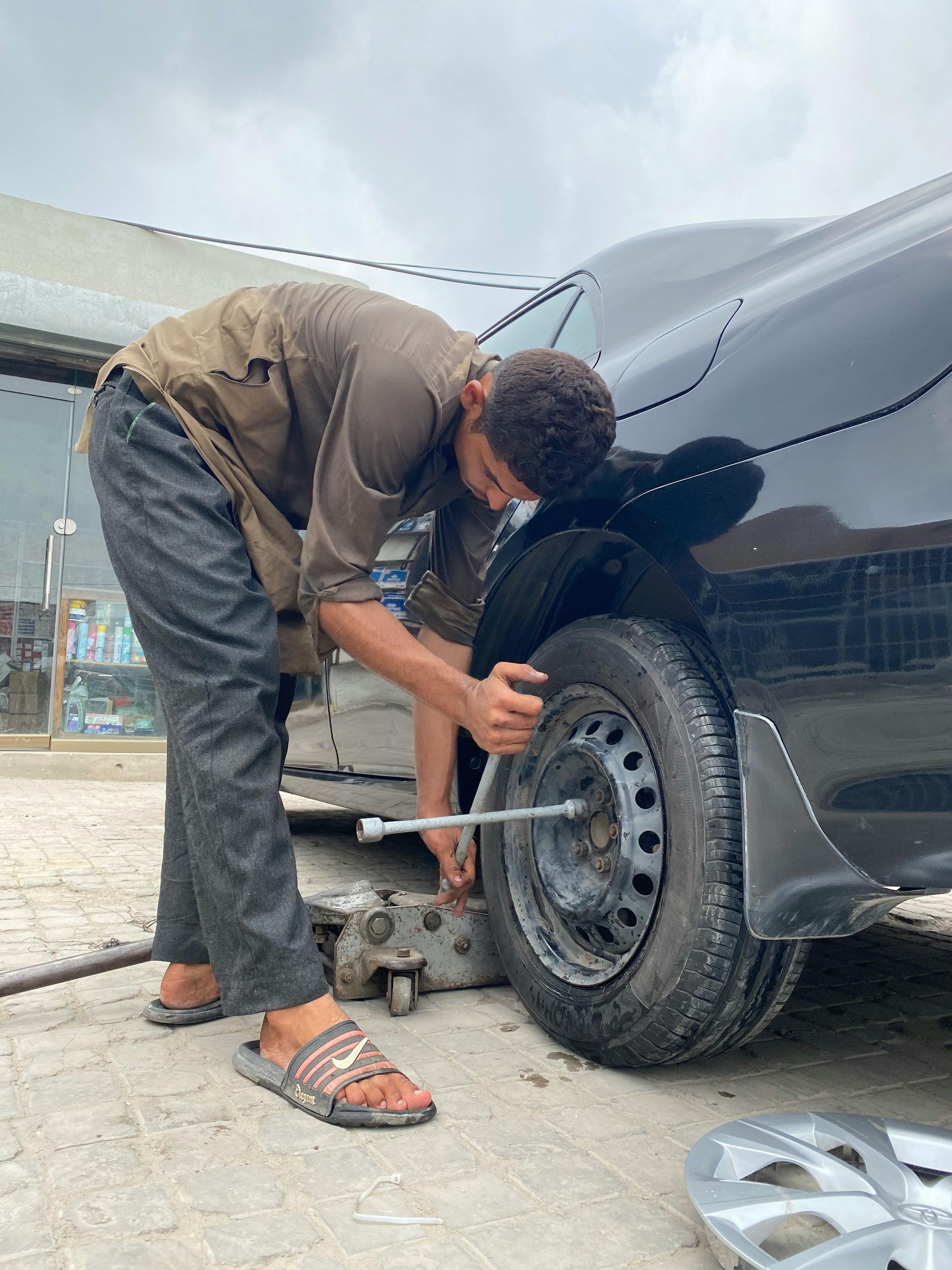 A man is changing a tire on a black car.