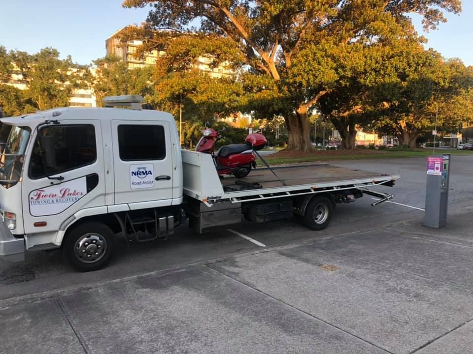 A Tow Truck Is Towing a Motorcycle in A Parking Lot — Twin Lakes Towing & Recovery in Berkeley Vale, NSW