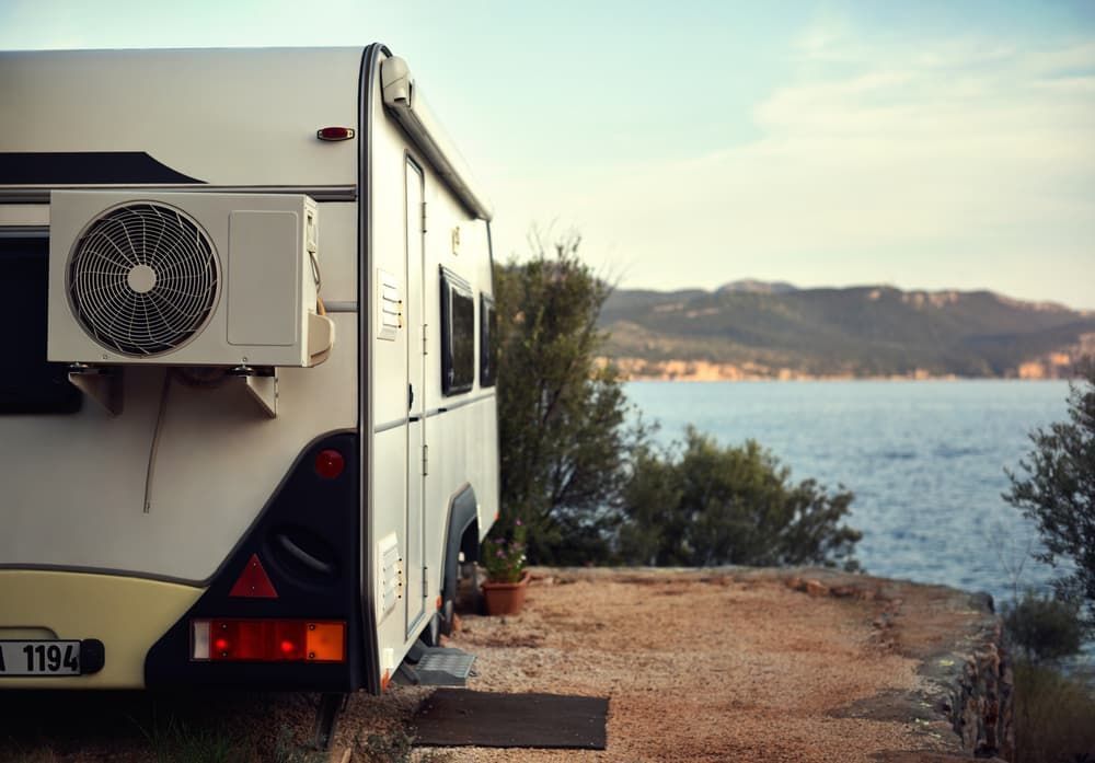 A Rv with A Fan on The Side Is Parked Next to A Body of Water — Twin Lakes Towing & Recovery in Cessnock, NSW