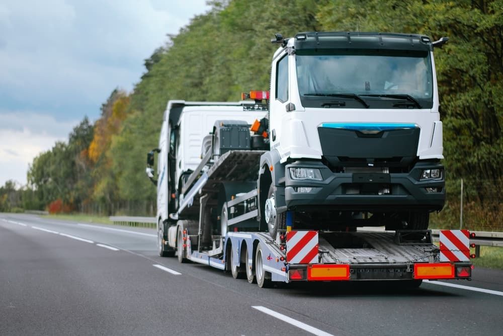 A Tow Truck Is Driving Down a Highway with A Car on The Back of It — Twin Lakes Towing & Recovery in Charlestown, NSW