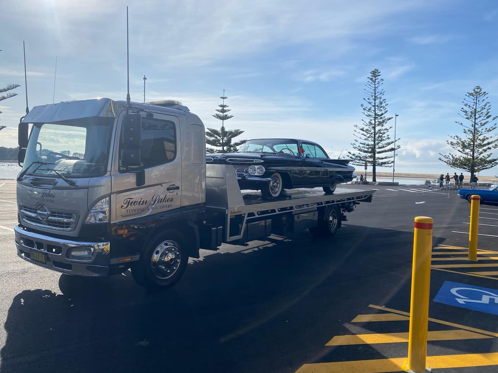 A Tow Truck Is Towing a Car in A Parking Lot — Twin Lakes Towing & Recovery in Thornton, NSW