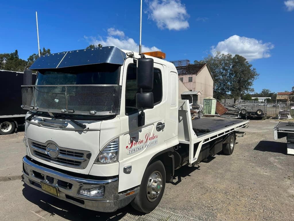 A White Tow Truck Is Parked in A Gravel Lot — Twin Lakes Towing & Recovery in Rutherford, NSW
