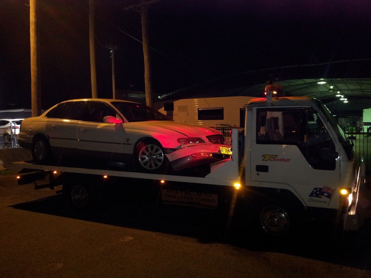 A White Car Is Being Towed by A Tow Truck — Twin Lakes Towing & Recovery in Cessnock, NSW