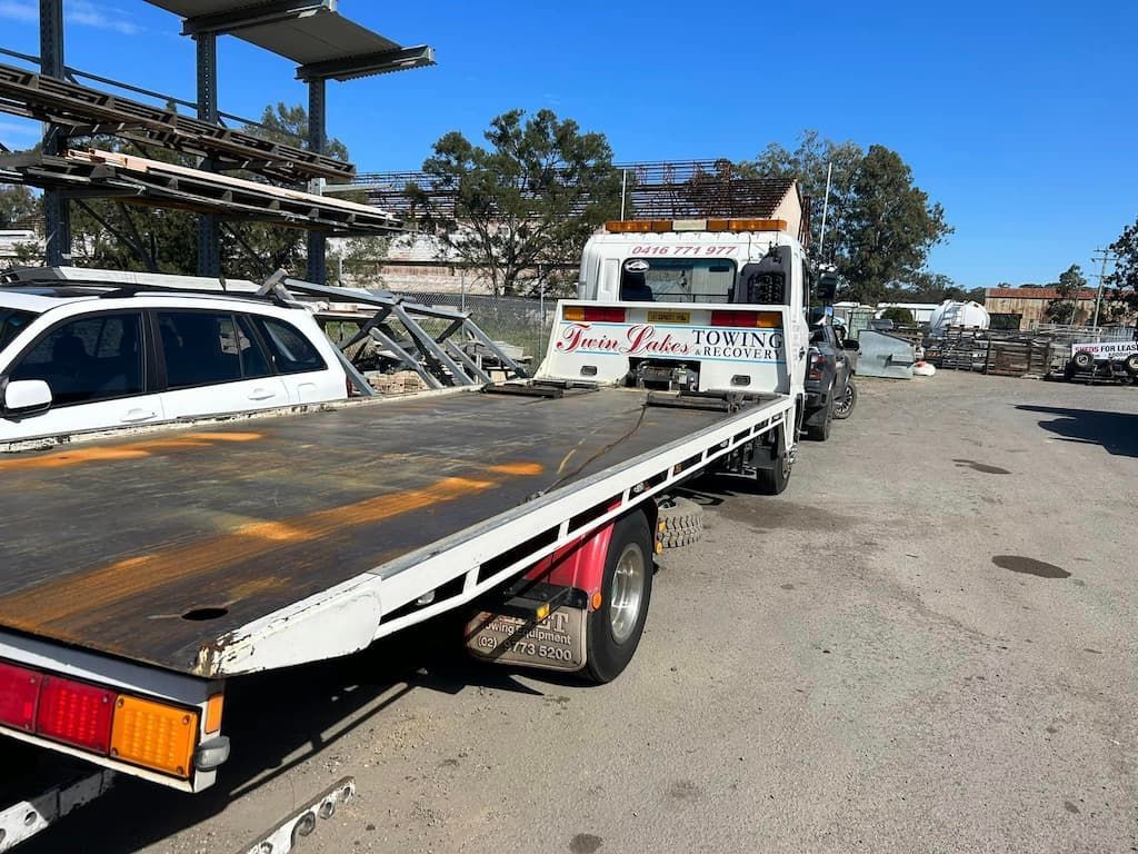 A Tow Truck with A Flat Bed Is Parked in A Parking Lot — Twin Lakes Towing & Recovery in Hamlyn Terrace, NSW