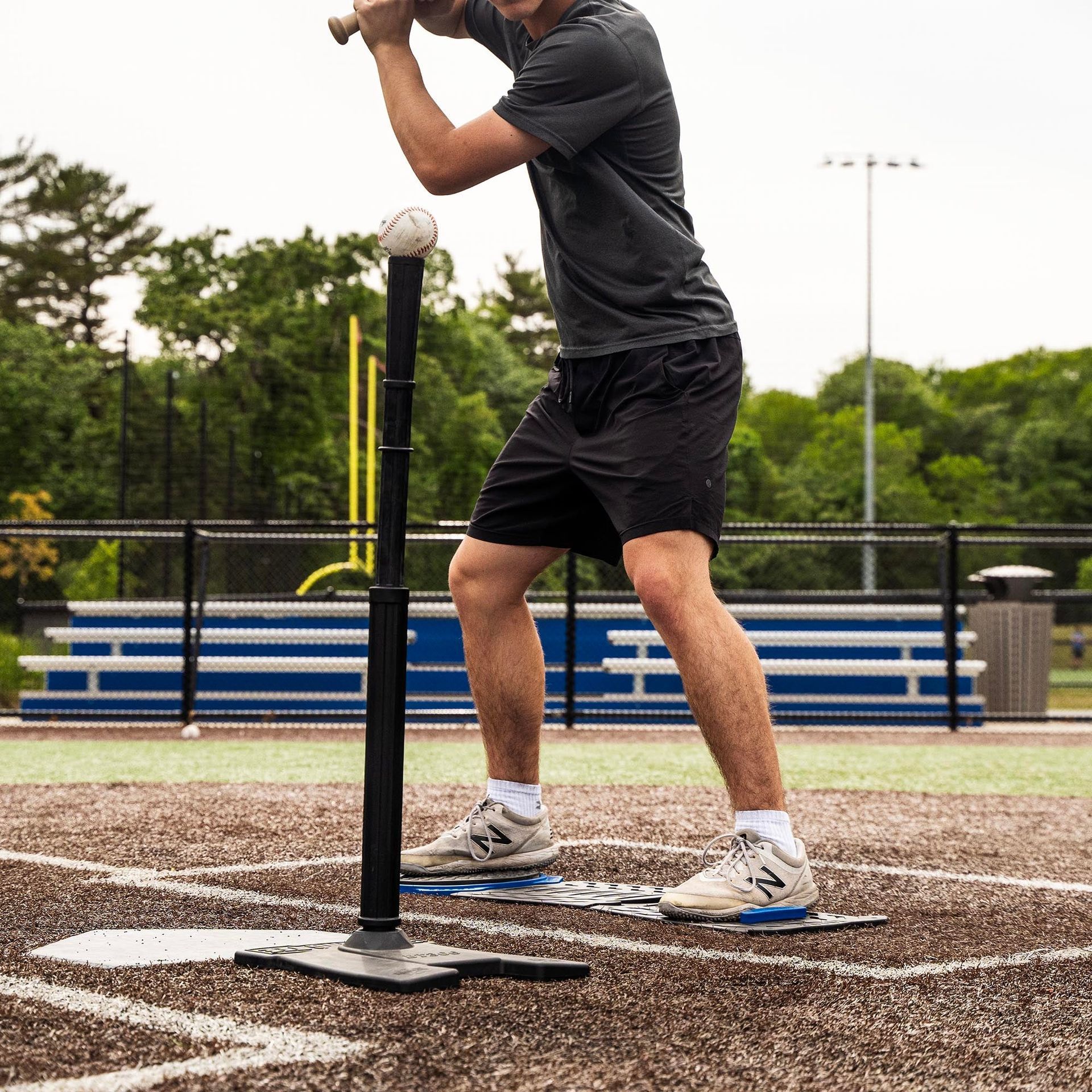 A man is swinging a bat at a baseball on a base
