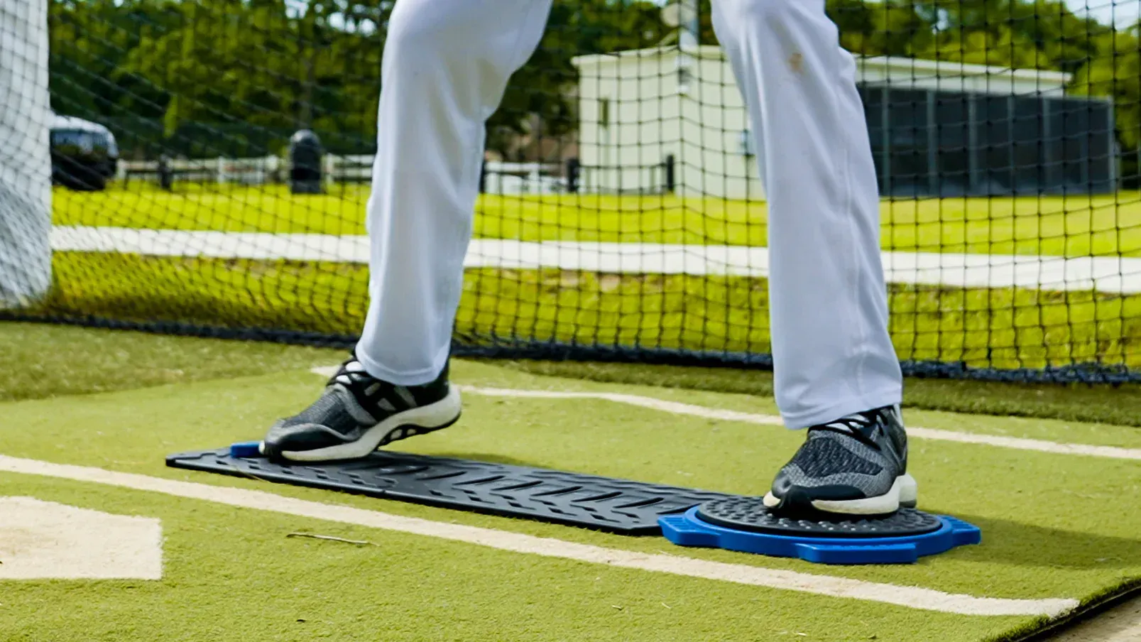 A baseball player is standing on a mat on a baseball field.
