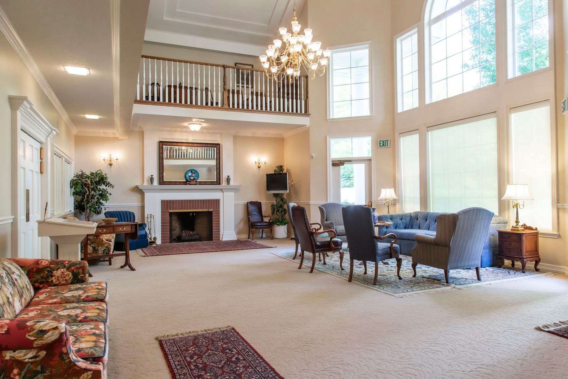 Spacious waiting room with fireplace, seating, and a second-story balcony. Natural light streams in through tall windows.