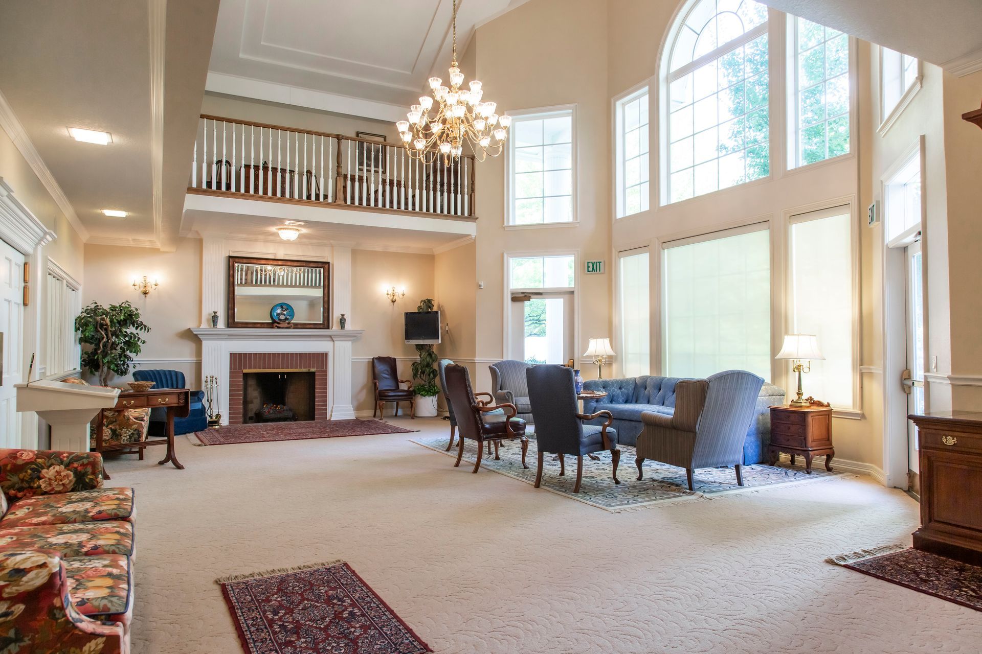 Spacious, light-filled room with high ceilings, fireplace, seating area, and large windows.