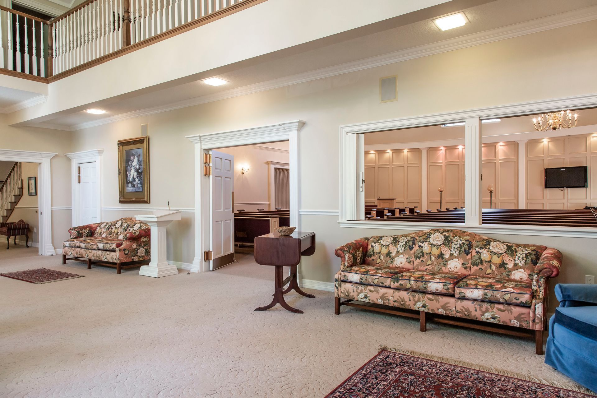 Interior of a large room with floral couches, a small table, and open doorways.