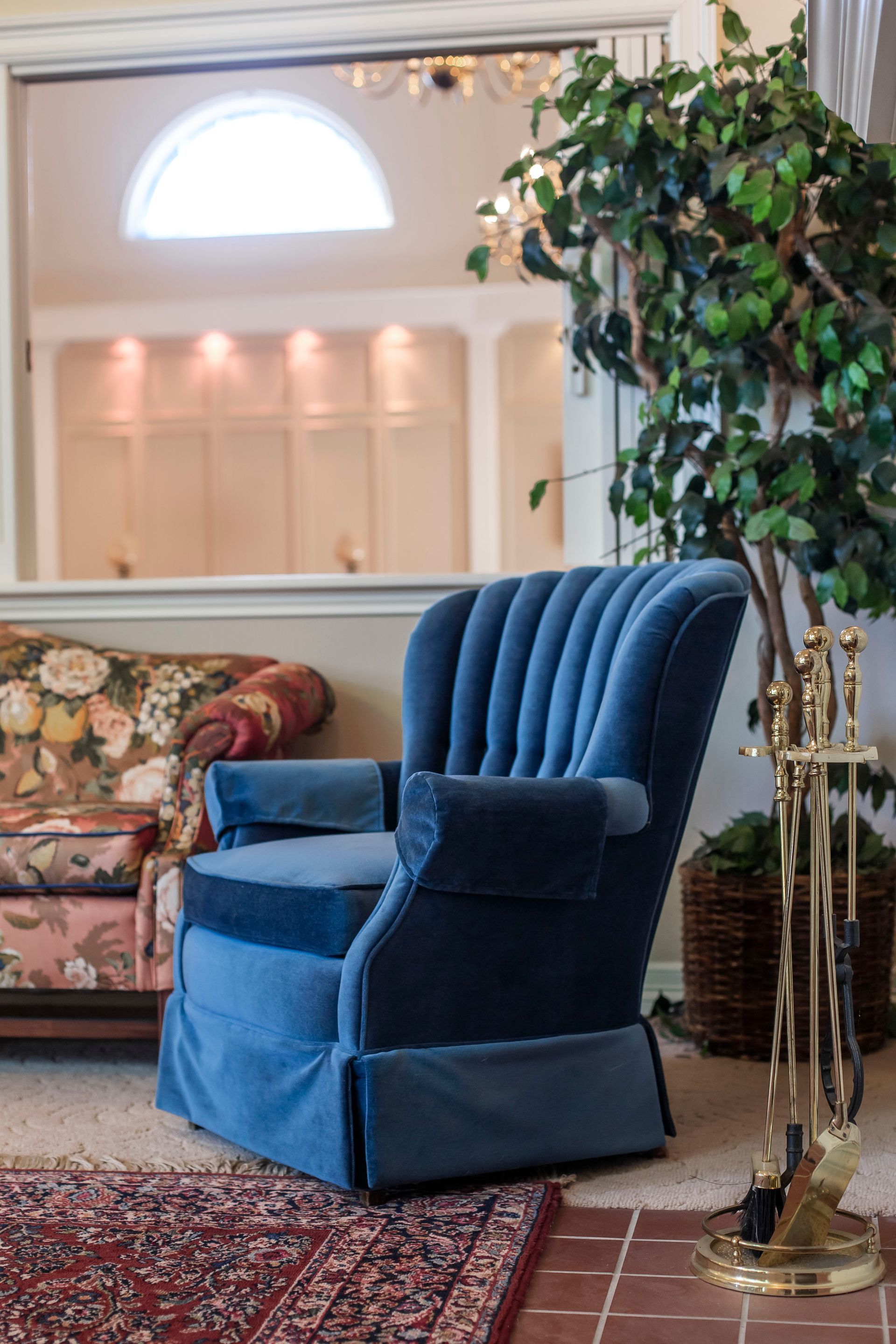 Blue velvet armchair in a room with a large mirror and potted plant.