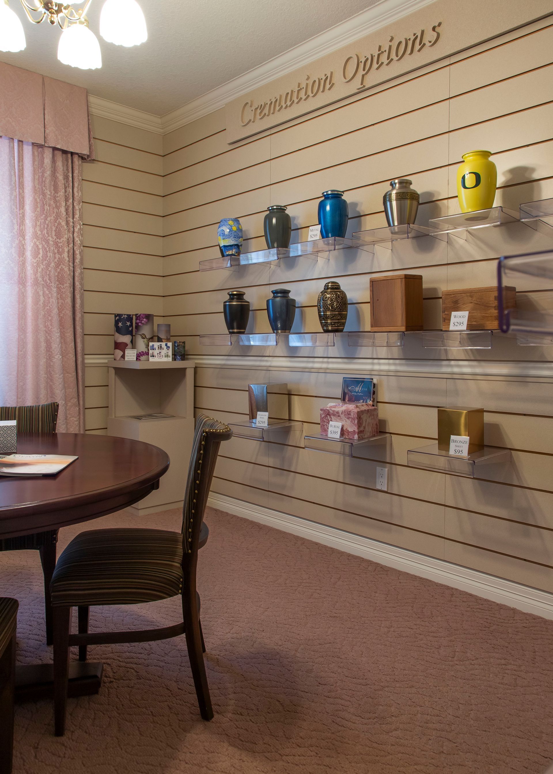 Interior room with cremation urns displayed on shelves, a table, and chair.