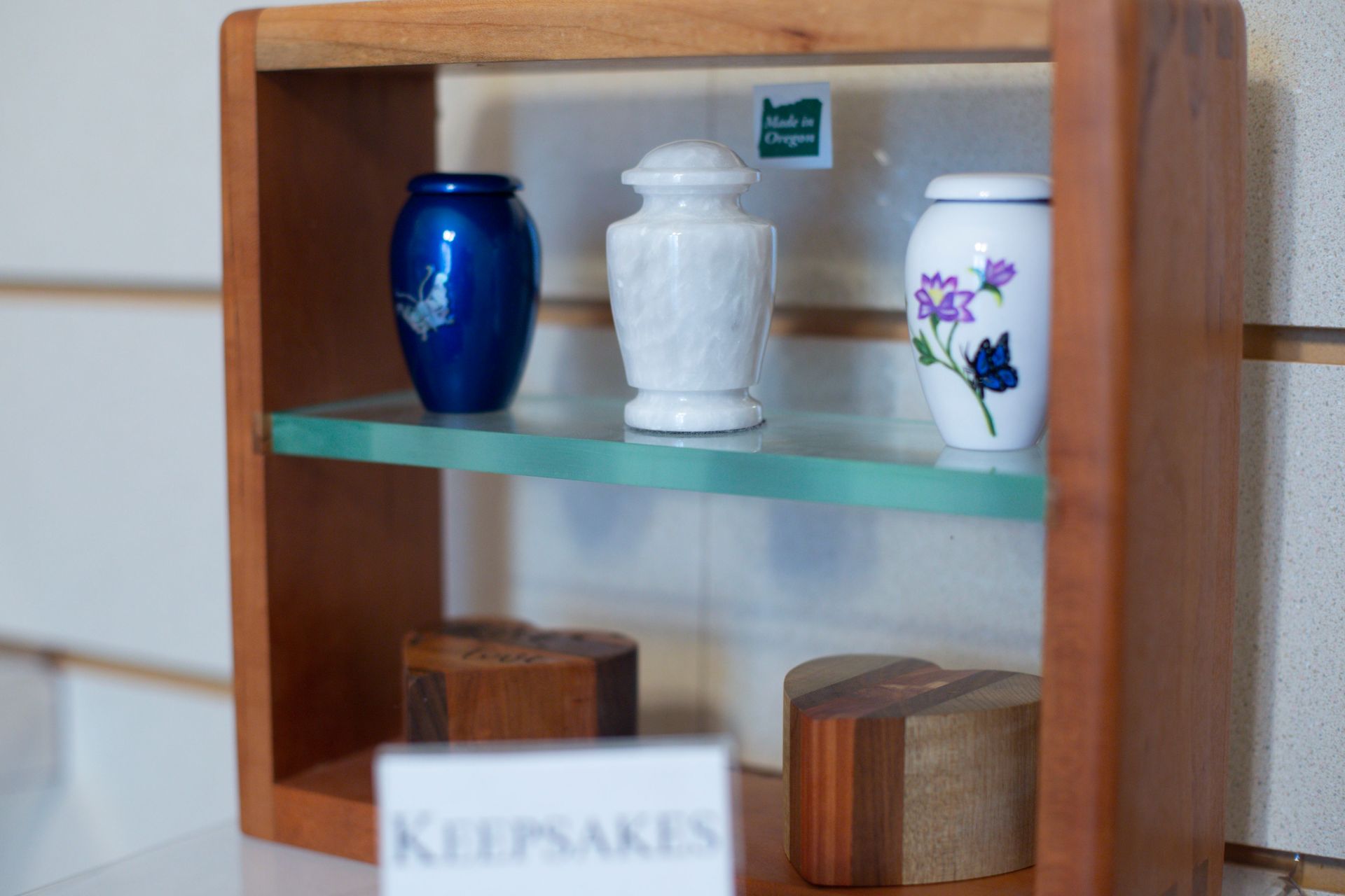 Display shelf with three small urns in blue, white, and floral designs.