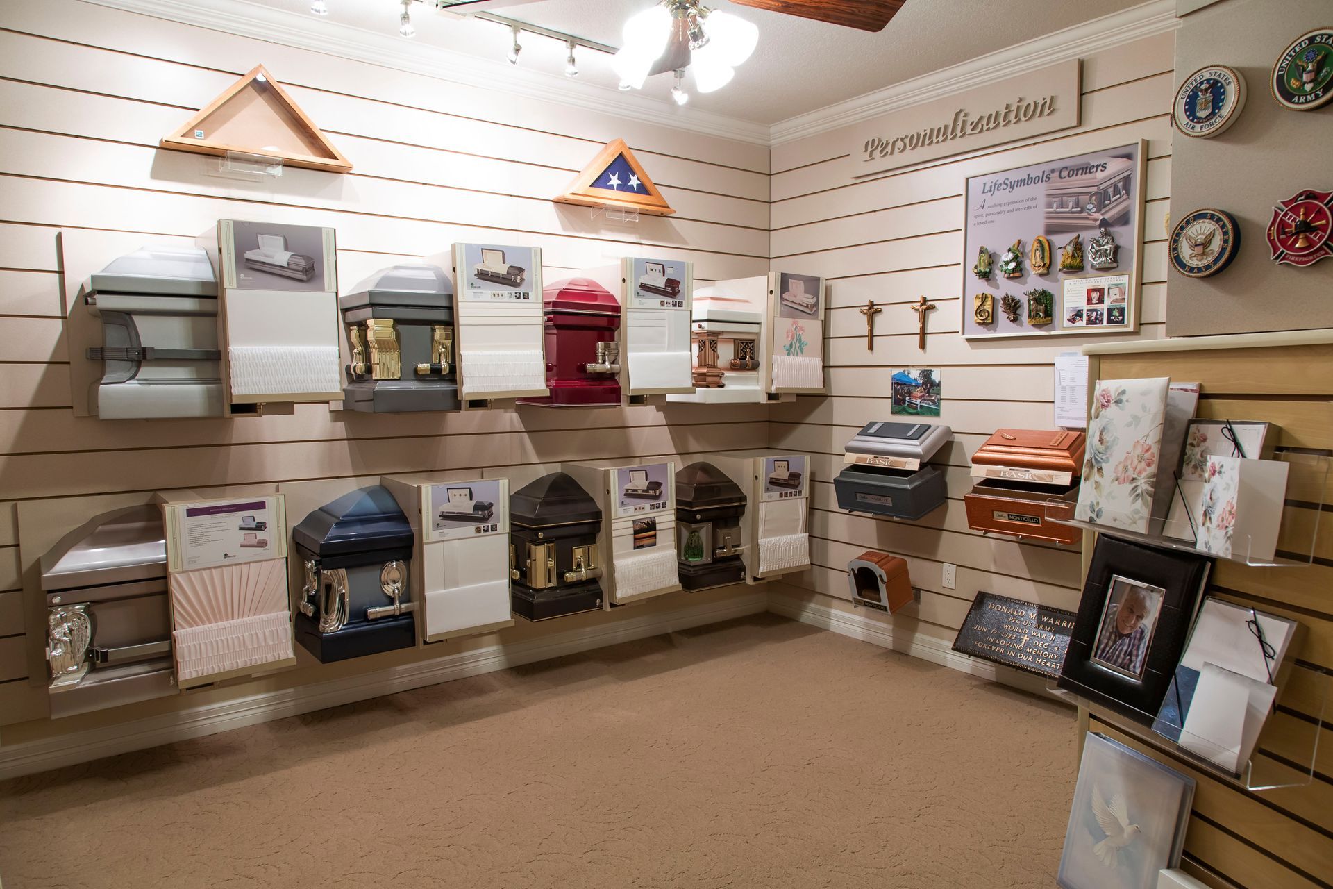 Room with wall display of cremation urns in various styles, sizes, and colors.