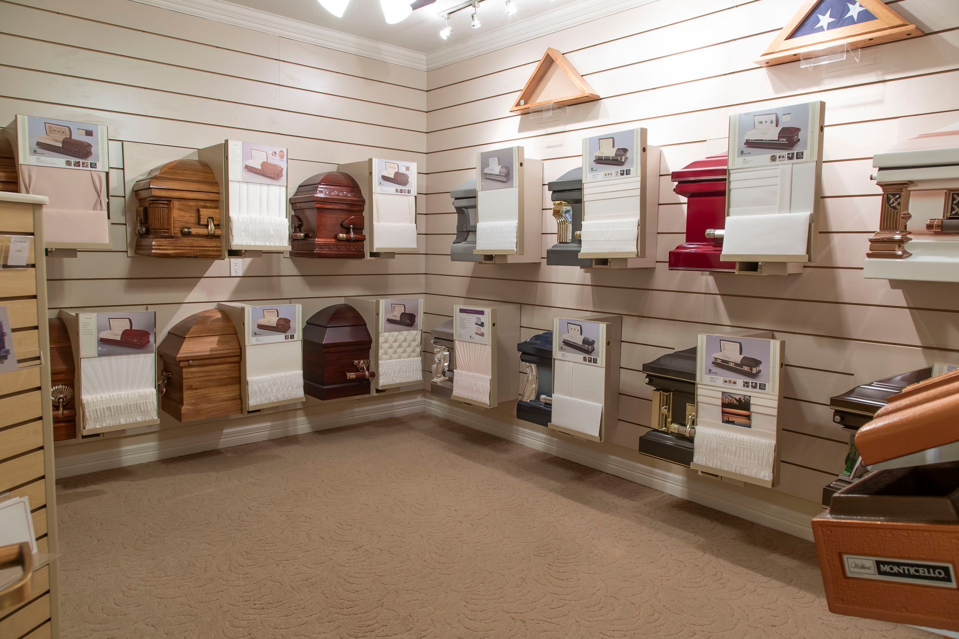 Interior of a funeral home displaying a variety of caskets on the walls.