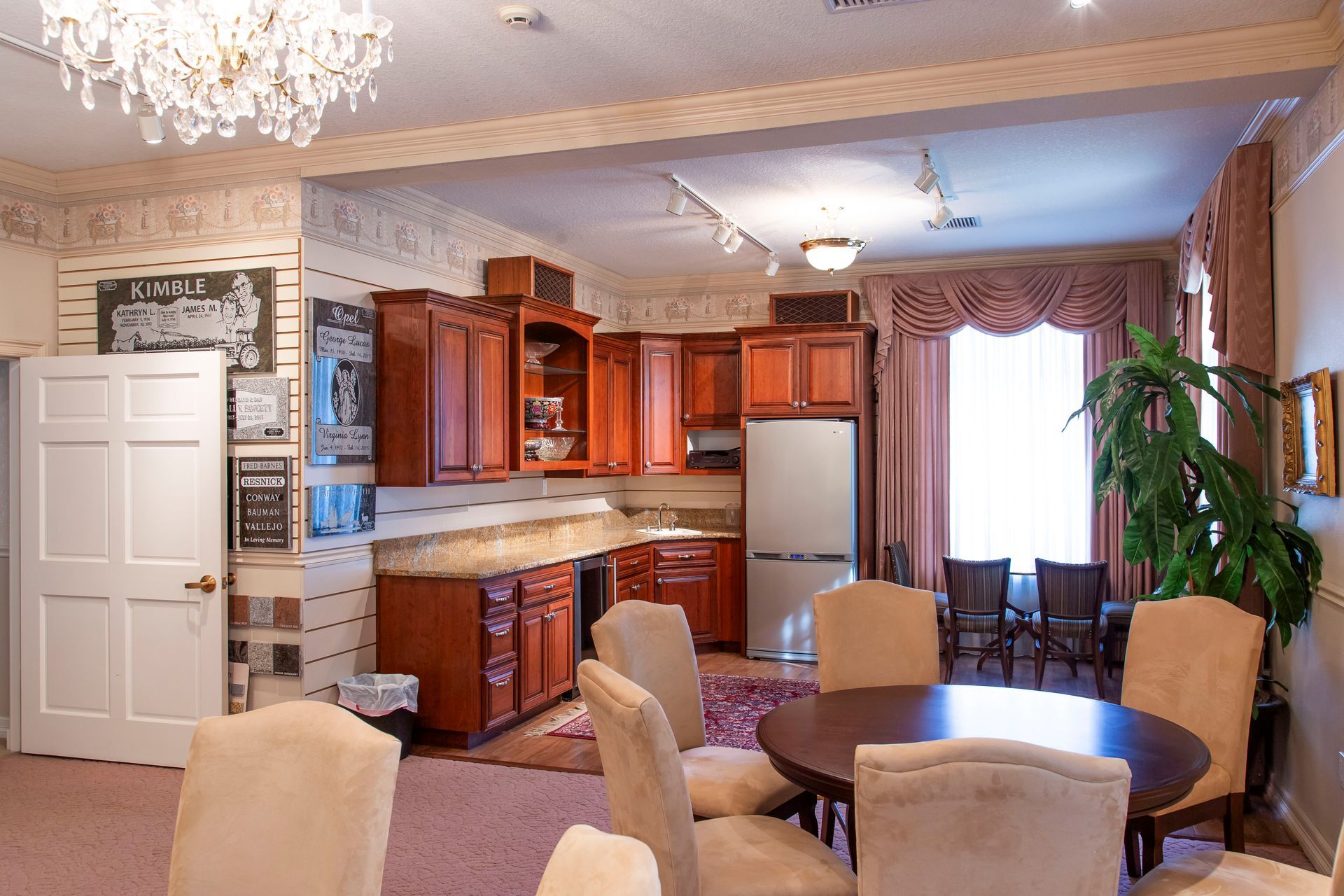 Interior room with kitchen cabinets, dining table, chairs, and a chandelier.