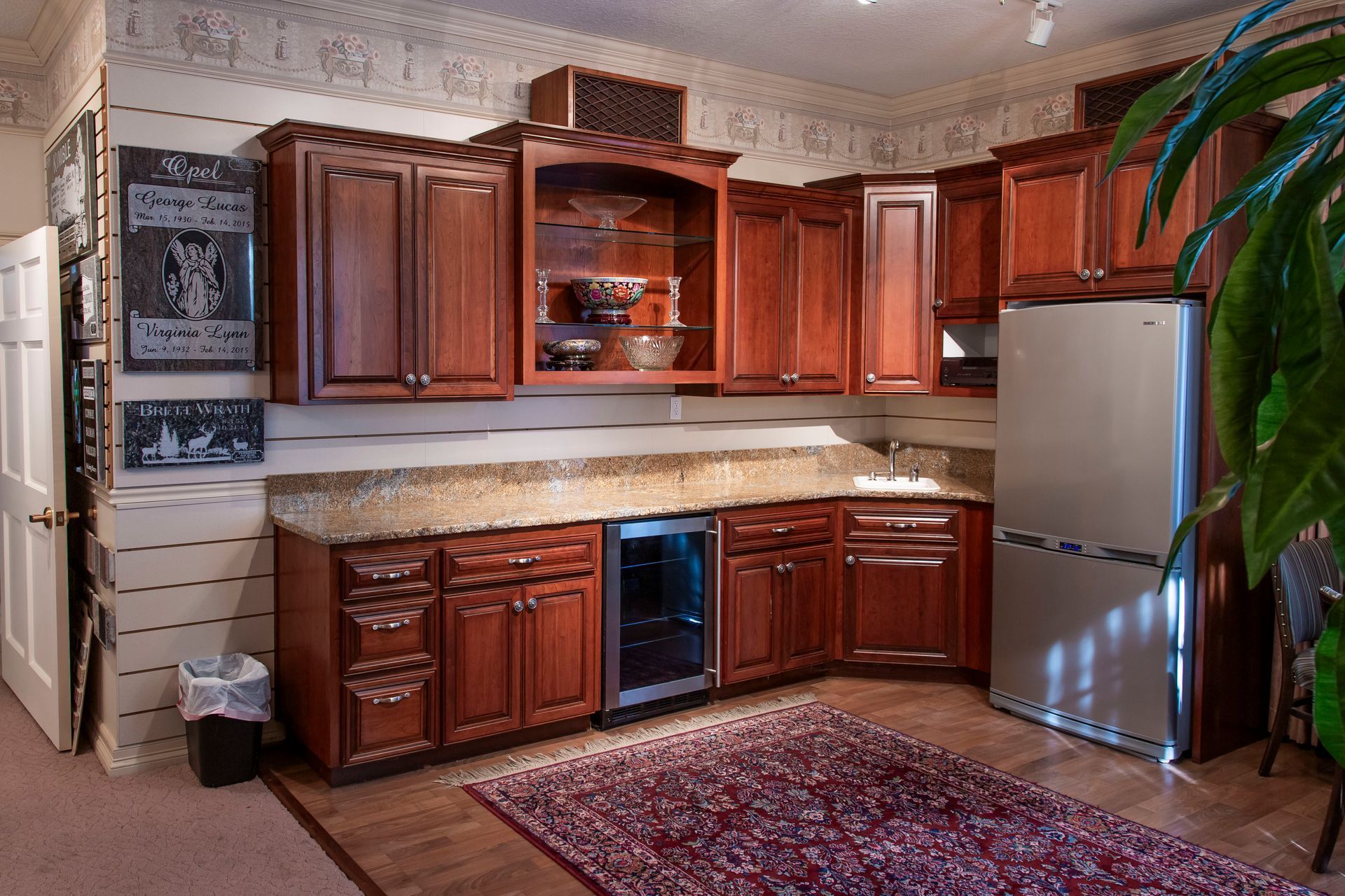 Kitchen with dark wood cabinets, granite countertop, stainless steel refrigerator, and wine cooler.