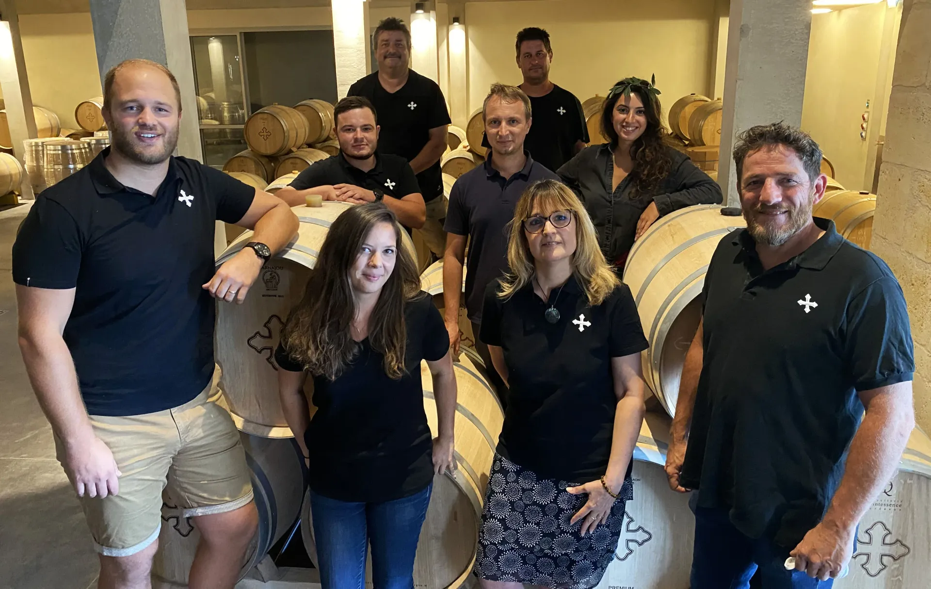 Group of people in Château de Chambrun winery, posing by barrels.