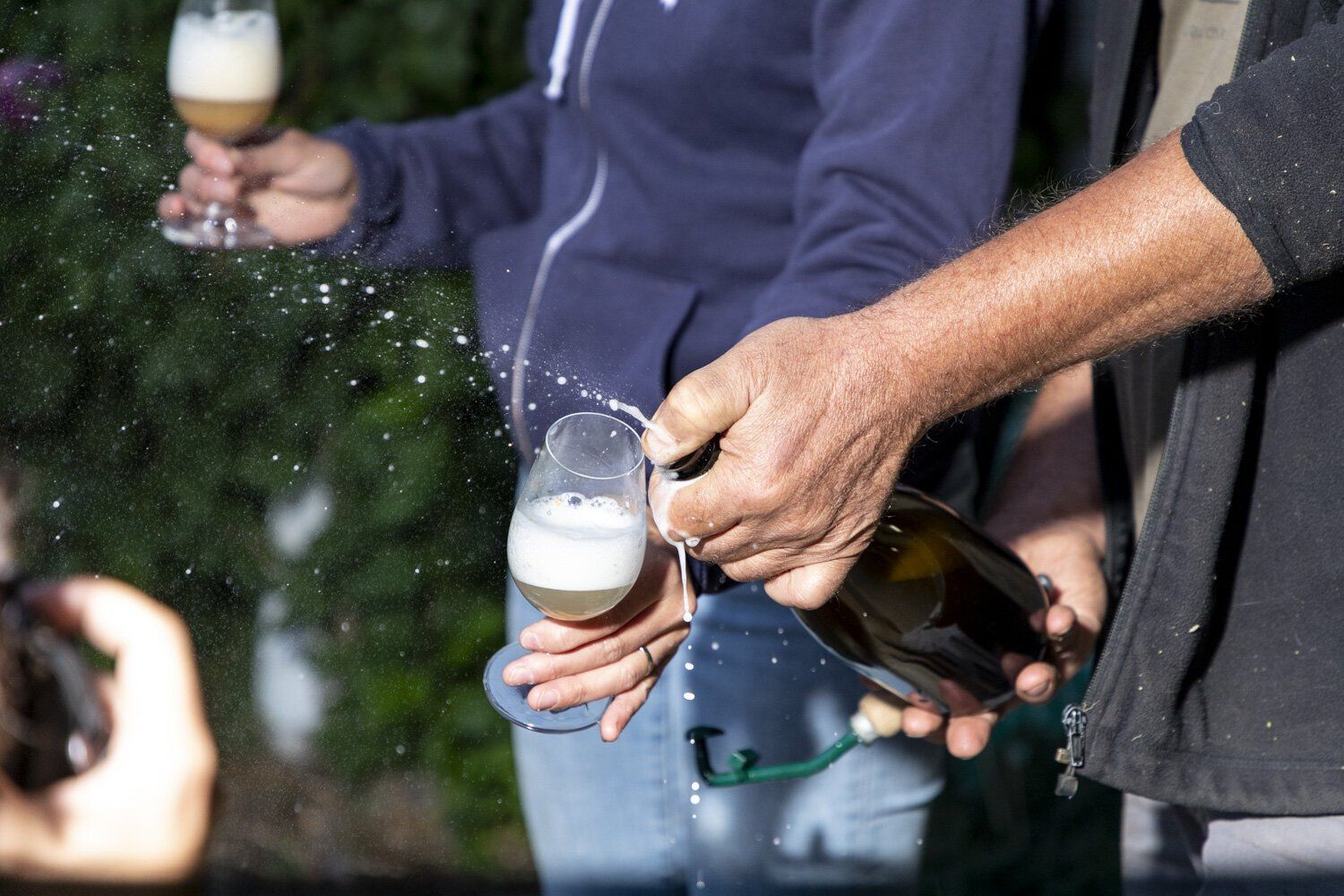 A man is pouring champagne into a glass while a woman holds a glass.