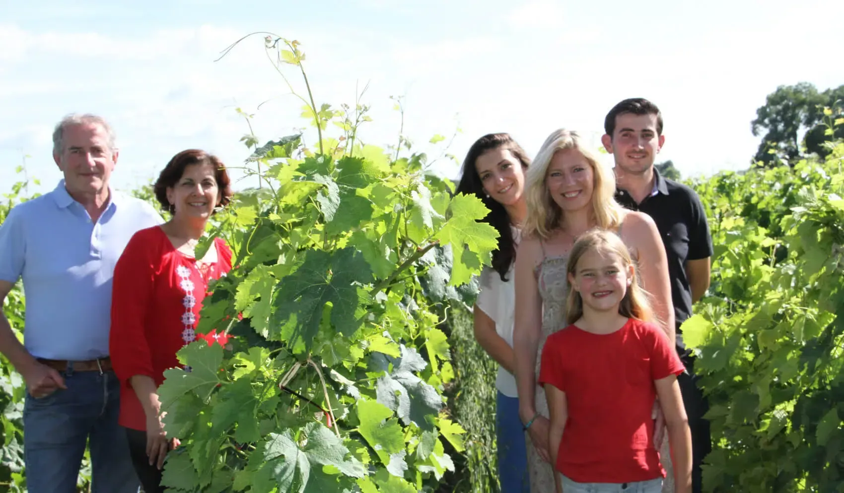 Château Bellegrave family standing among grape vines at the vineyard.