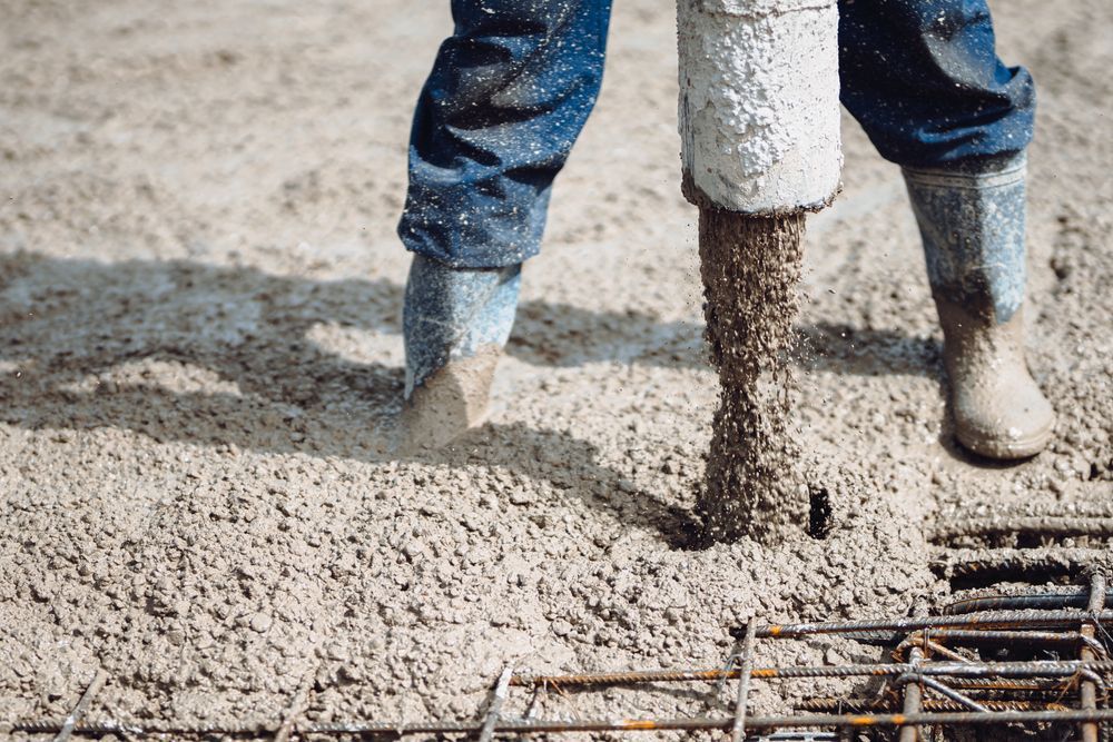 Person Pouring Wet Concrete Onto a Rebar-lined Surface — East Point Earthmoving in Byron Bay, NSW