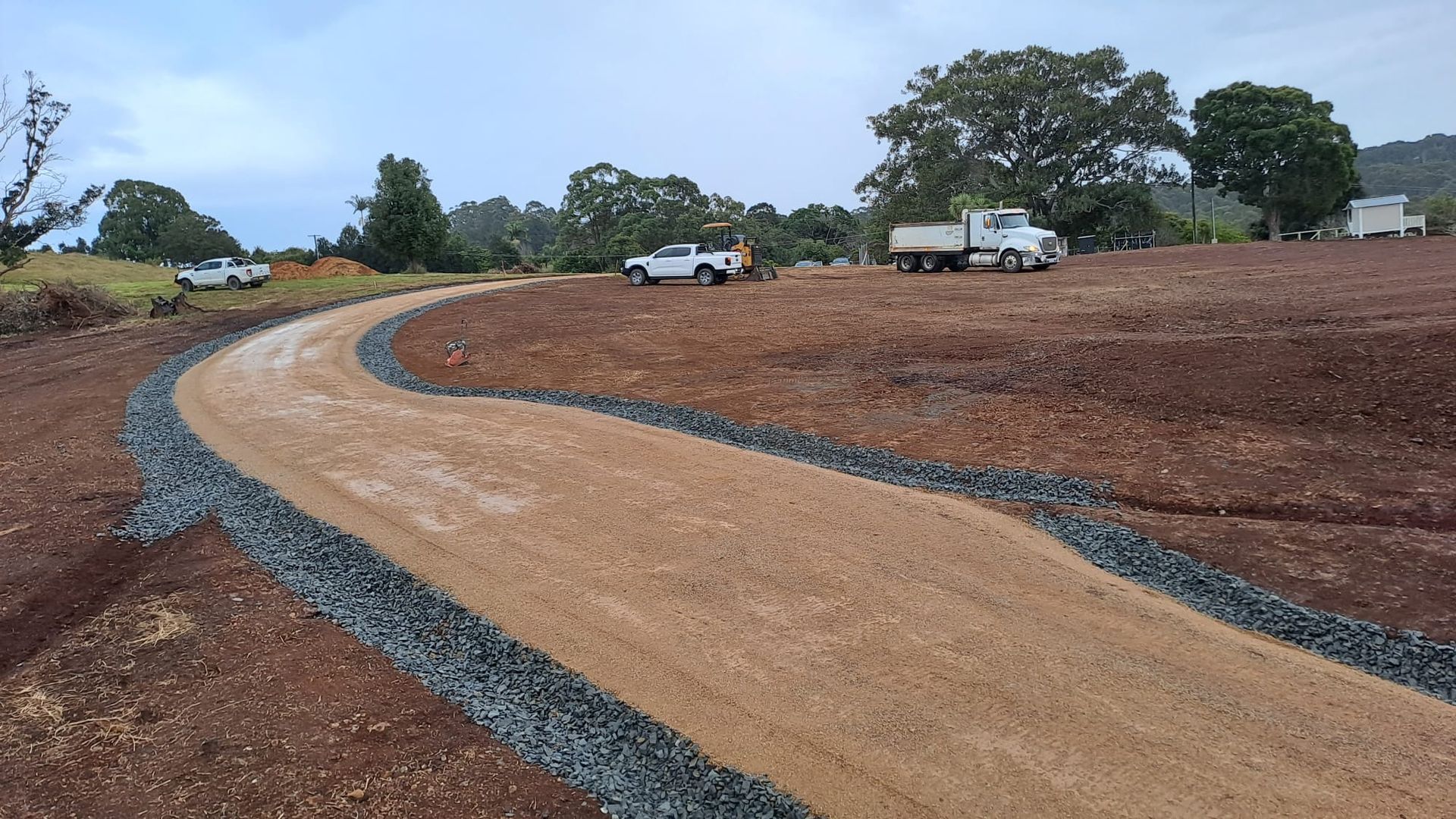A dirt road going through a field with a truck in the background