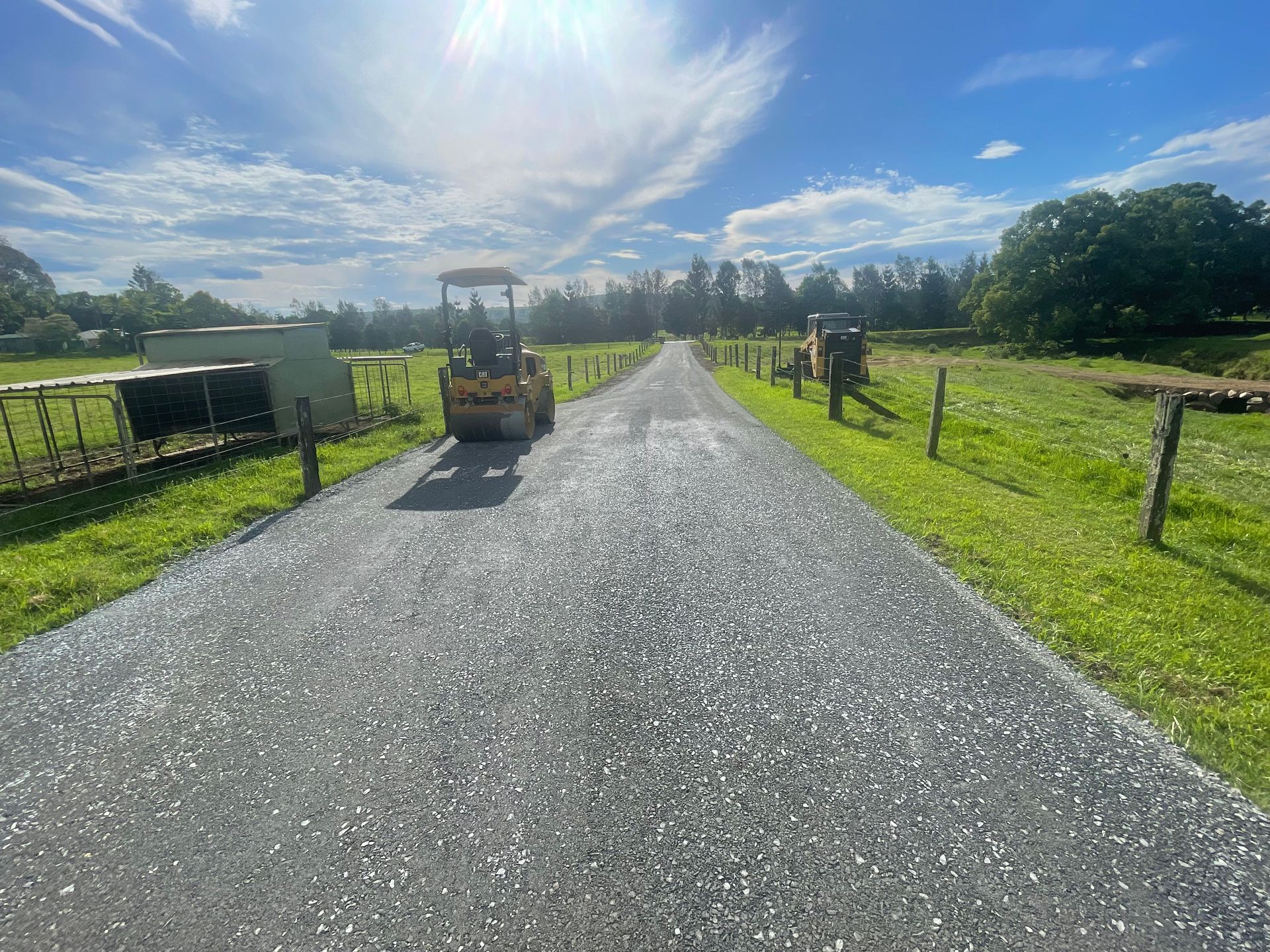 A Yellow Bulldozer Working On An Asphalt Road — East Point Earthmoving in Byron Bay, NSW