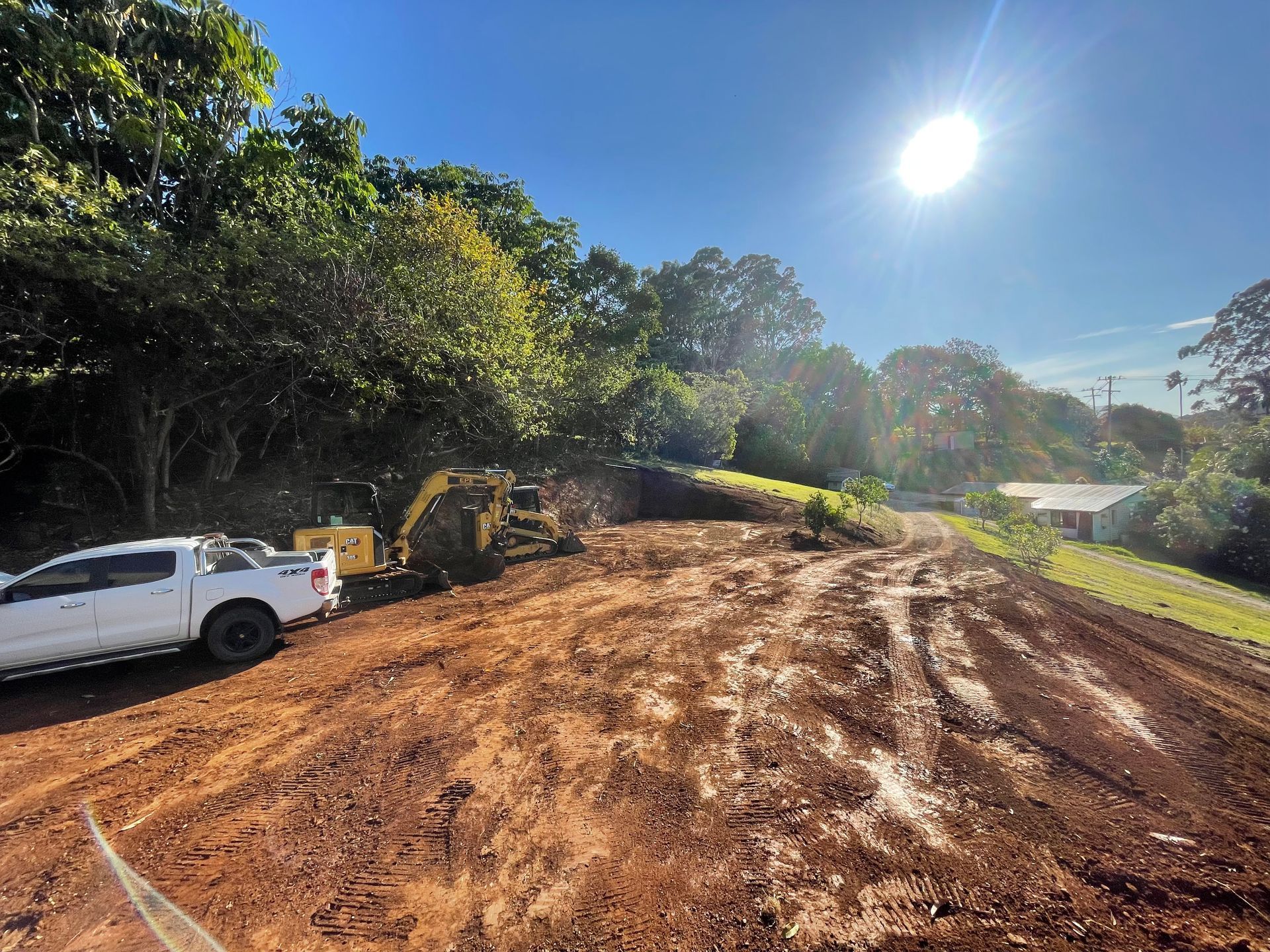 A Yellow Excavator Is Moving Dirt On A Dirt Road — East Point Earthmoving in Byron Bay, NSW