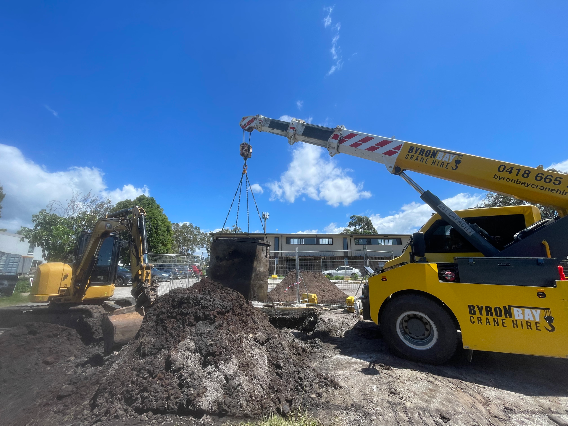 A yellow crane is lifting a large pile of dirt.