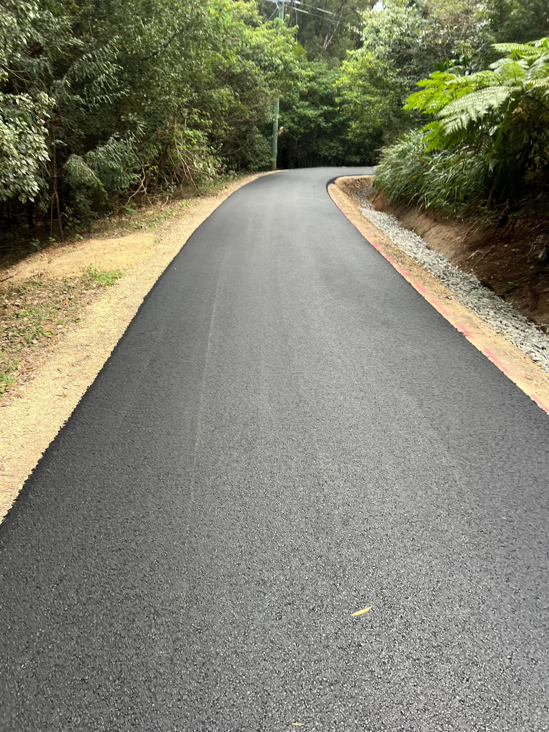 A Man Is Working On A Road With A Shovel — East Point Earthmoving in Byron Bay, NSW