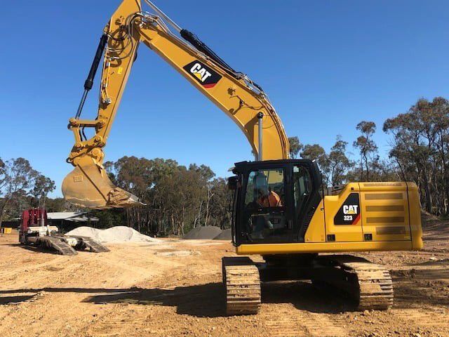 A Yellow Cat Excavator Is Sitting In The Dirt On A Construction Site — East Point Earthmoving in Bangalow, NSW