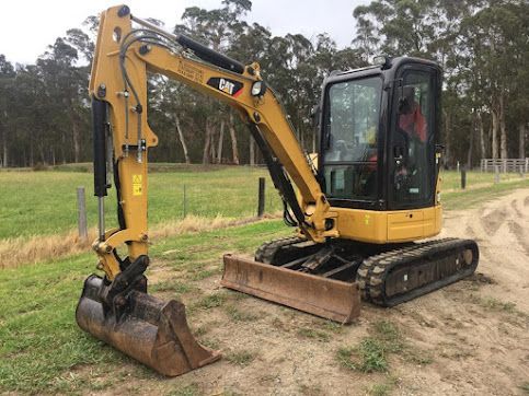 A Small Yellow Excavator Is Parked On The Side Of A Dirt Road — East Point Earthmoving in Lennox Head, NSW