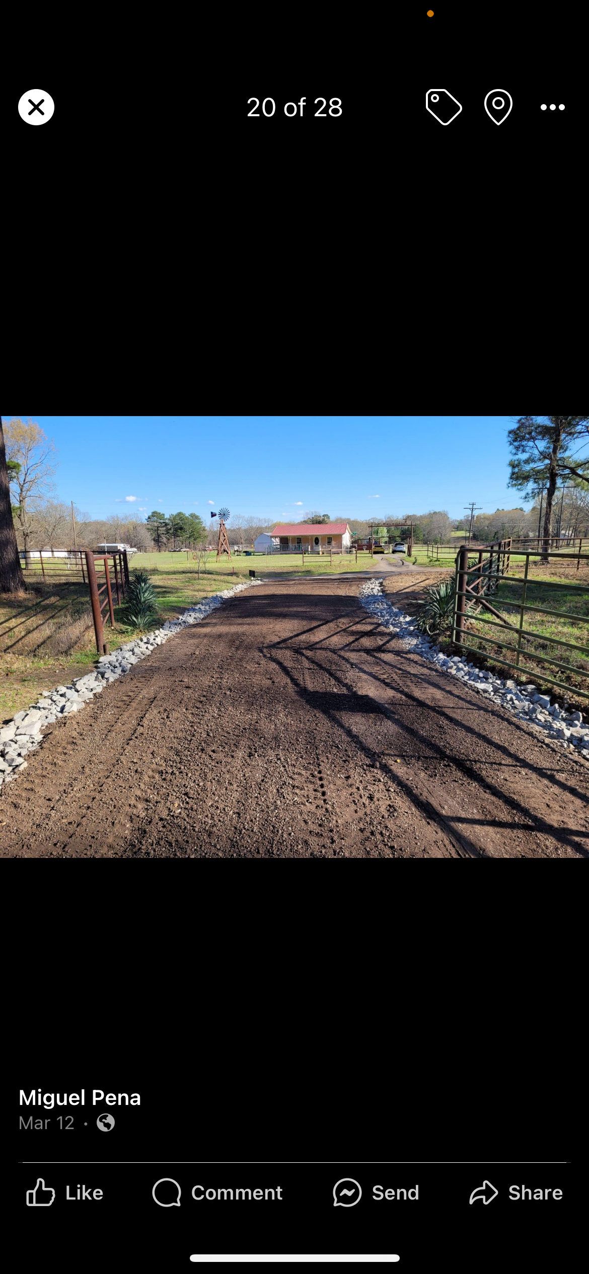 A gravel driveway leading to a house in a rural setting, under a clear blue sky.