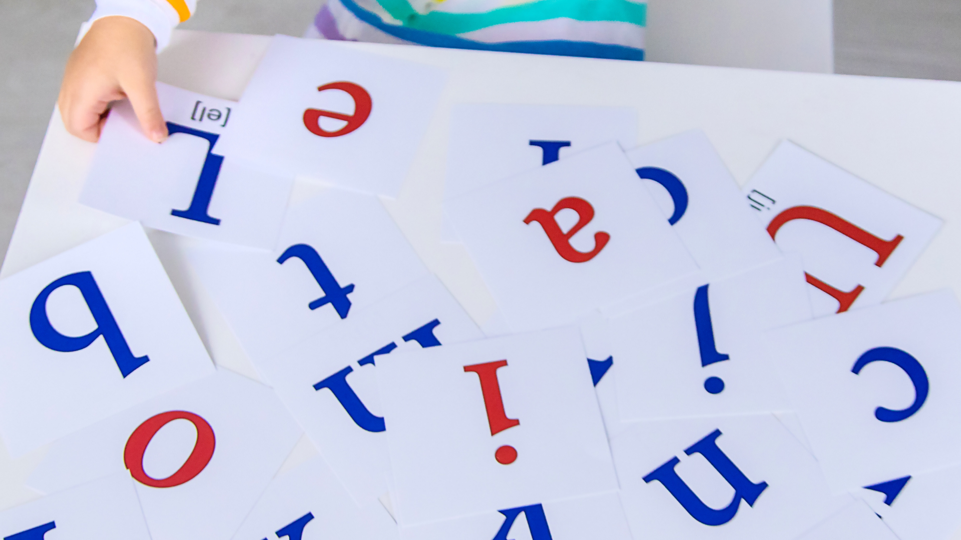 A child is playing with alphabet cards on a table