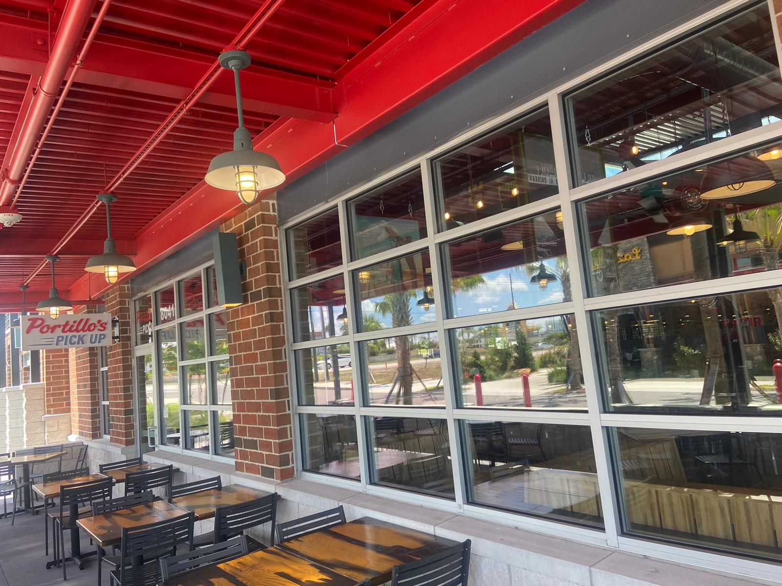 A restaurant with tables and chairs outside and lots of windows.