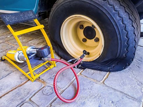 A car with a flat tire and a pump attached to it.