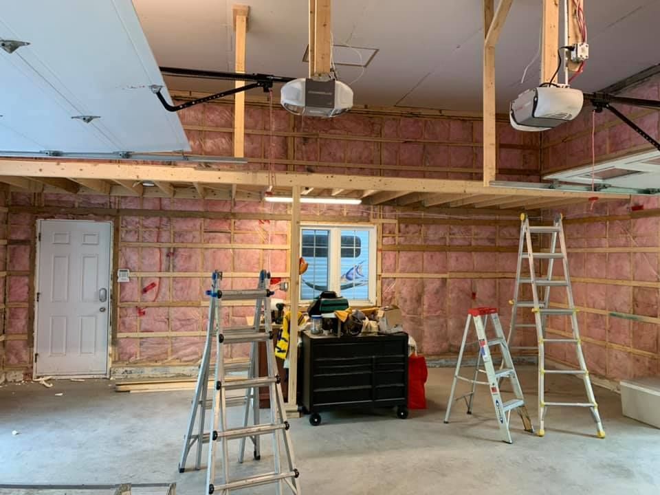 Un garage en construction avec échelles et ouvre-porte de garage.