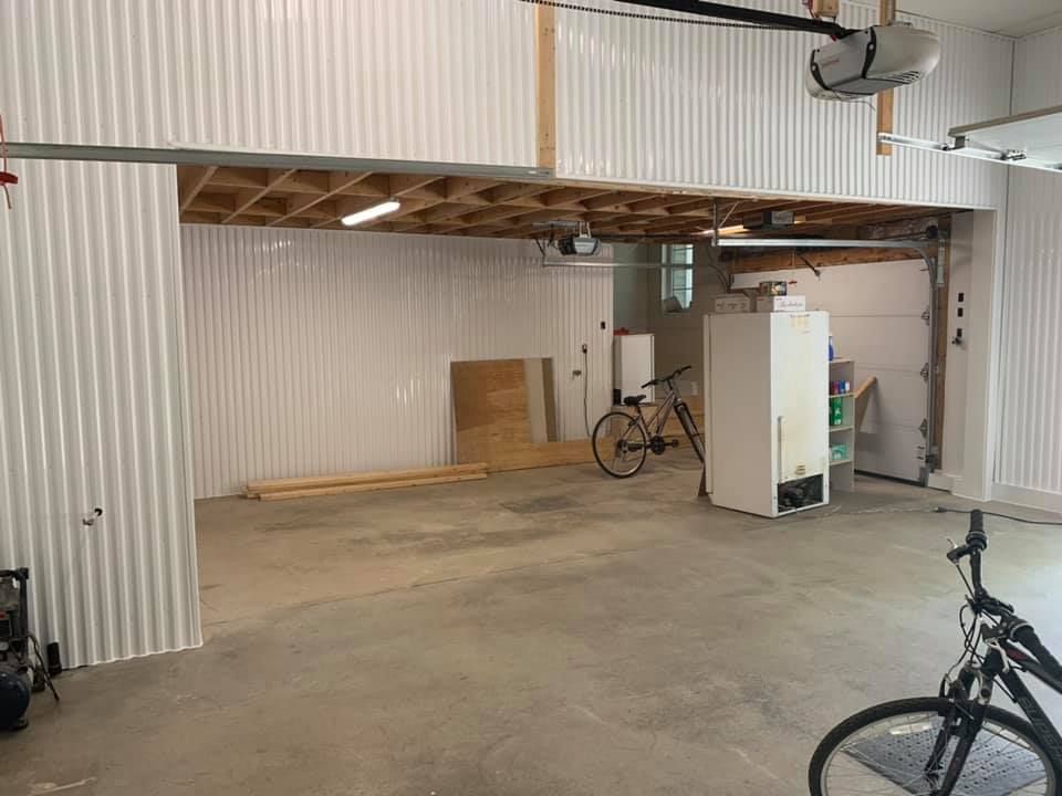 Un vélo est garé dans un garage à côté d'un réfrigérateur.