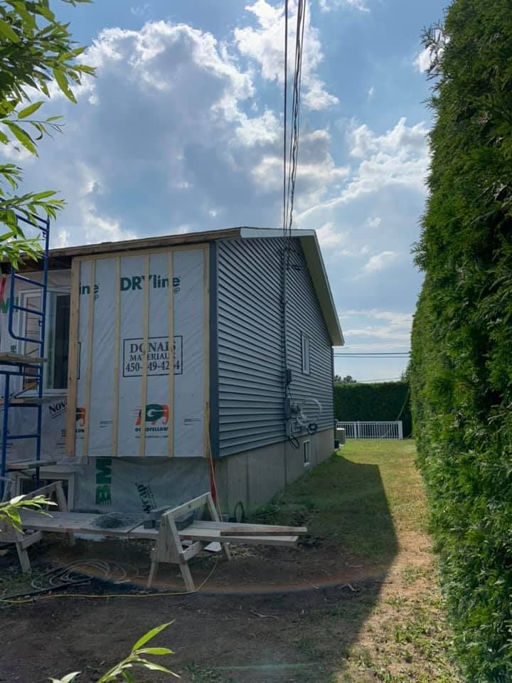 Une petite maison est en construction à côté d'une haie.
