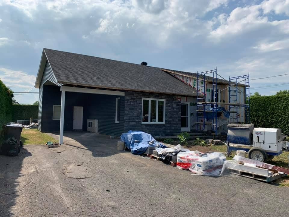 Une maison est en cours de rénovation avec un échafaudage et une remorque.