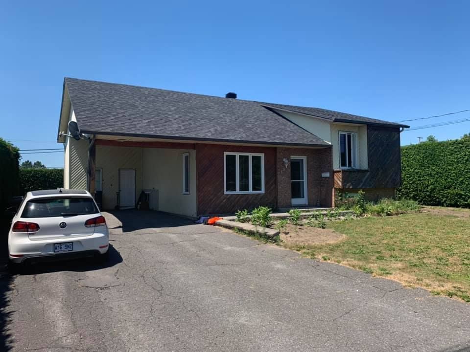 Une voiture blanche est garée devant une maison en briques.