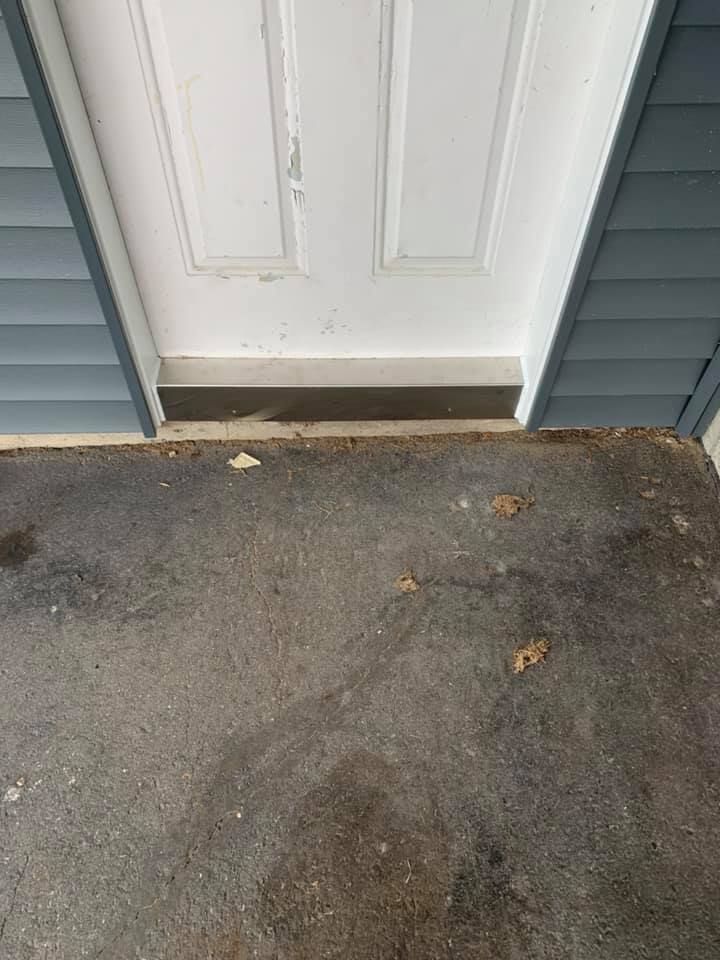 Une porte blanche est posée sur un sol en béton à côté d'une maison.