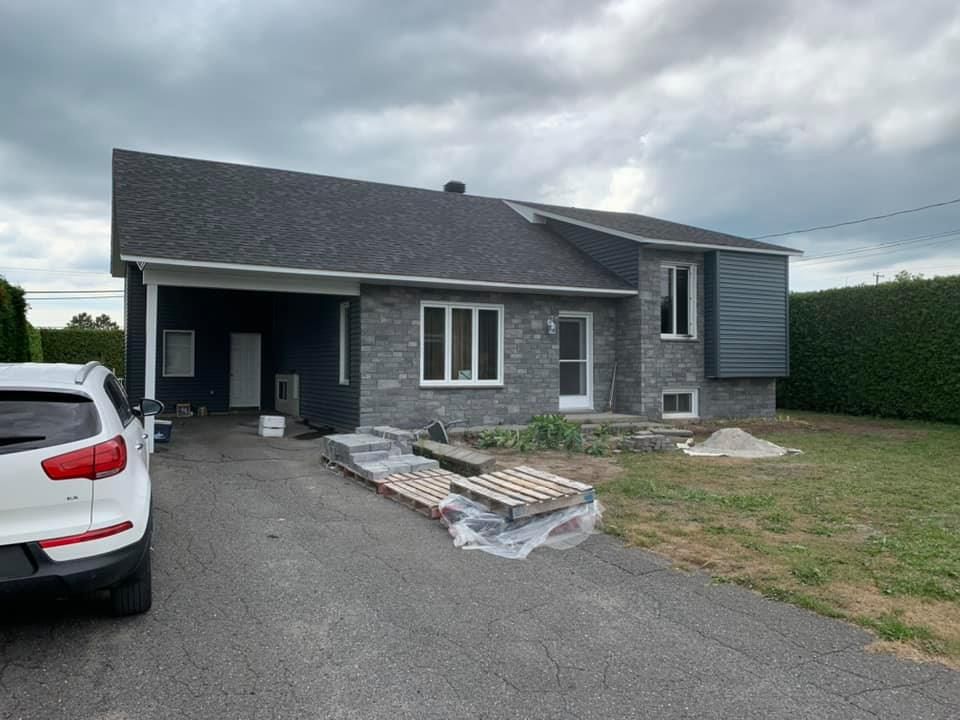 Une voiture blanche est garée devant une maison en briques.