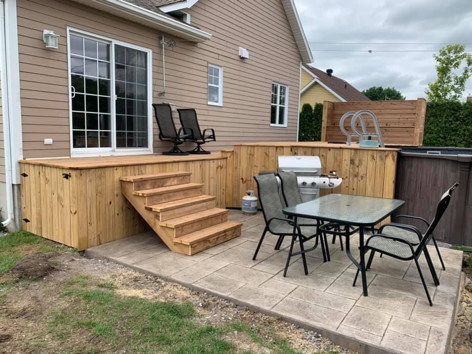 Une terrasse en bois avec une table et des chaises devant une maison.