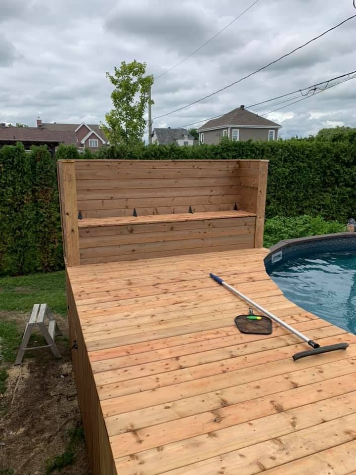Une terrasse en bois est en cours de construction à côté d'une piscine.
