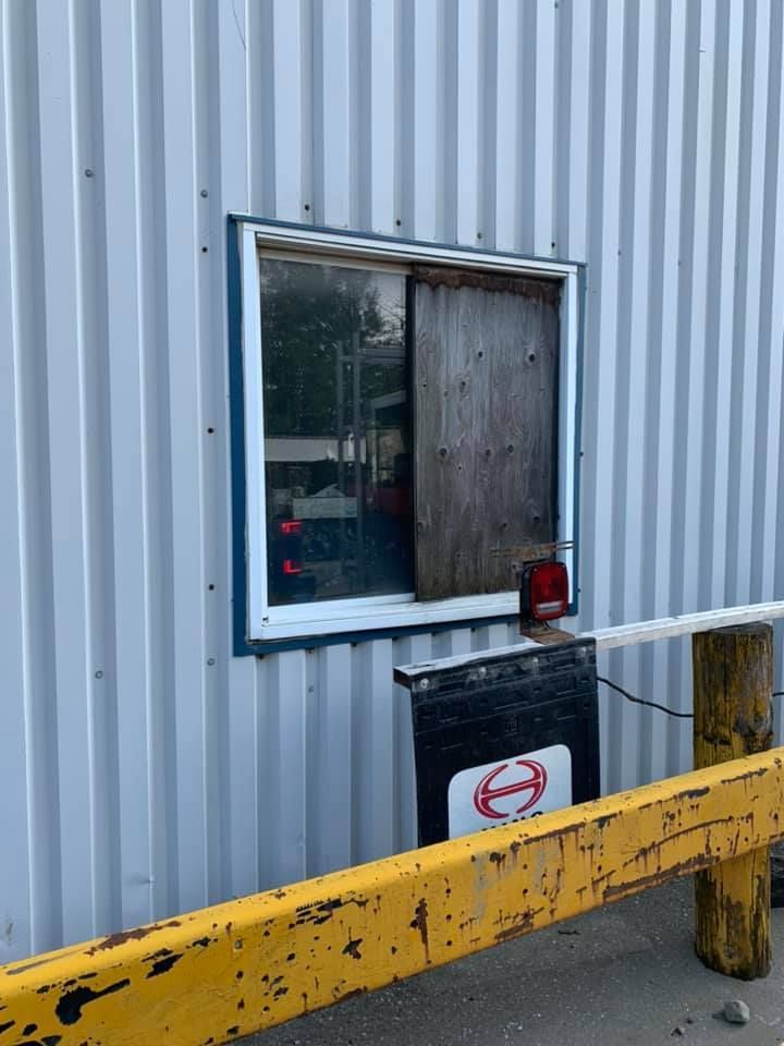 Une fenêtre sur le côté d'un bâtiment avec une barrière jaune.