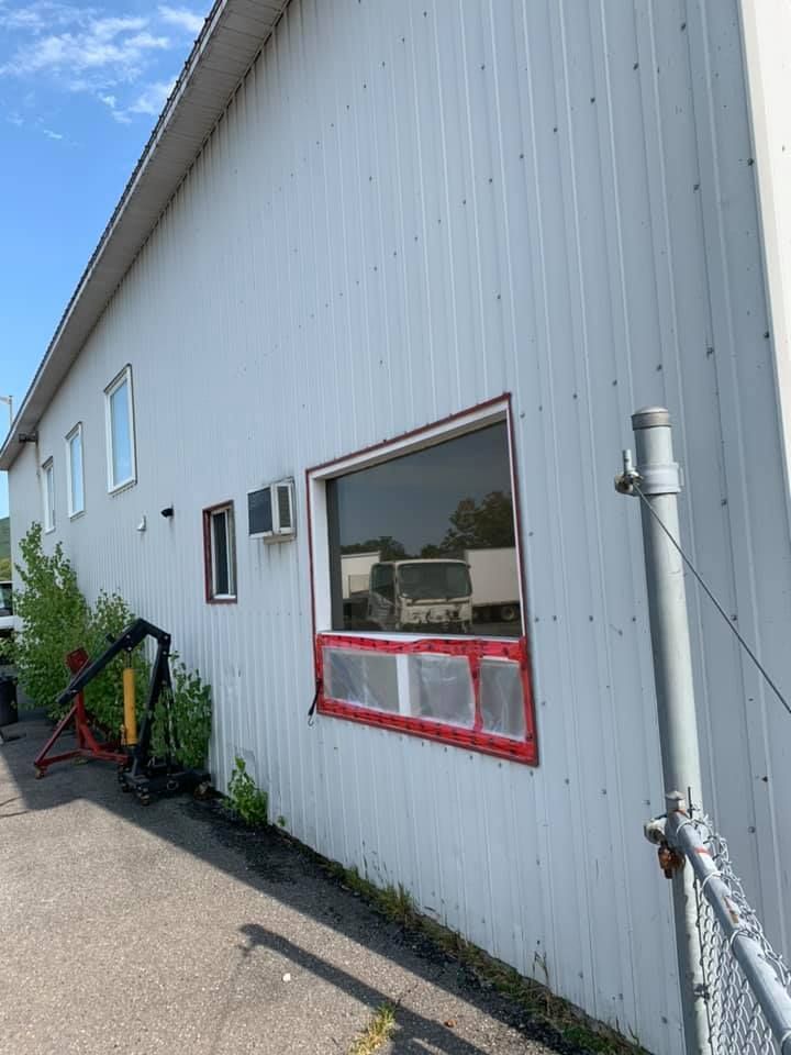 Un bâtiment blanc avec une fenêtre rouge et une clôture devant.