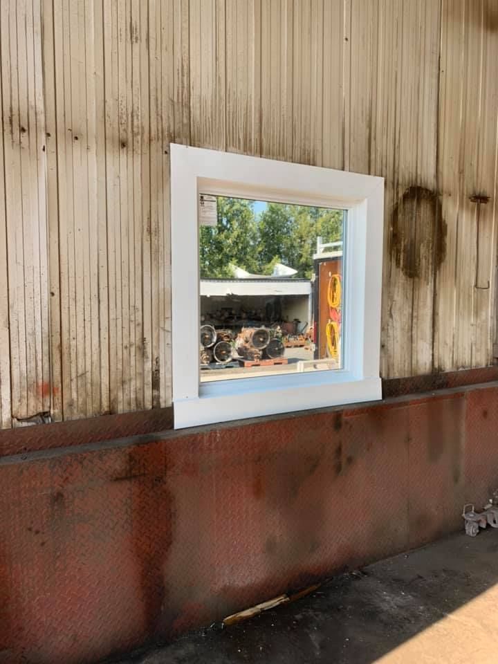 Une fenêtre avec un cadre blanc se trouve sur le côté d'un bâtiment.