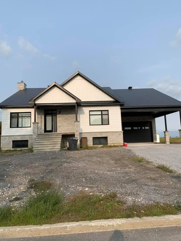 Une maison blanche avec un toit noir et un garage