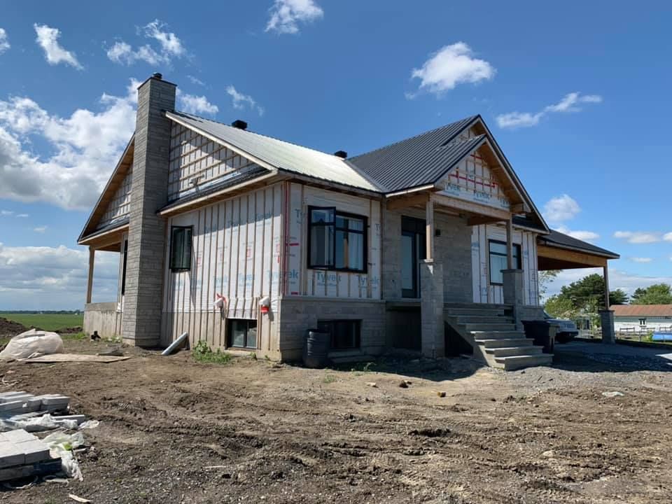 Une maison est en construction au milieu d'un champ de terre.