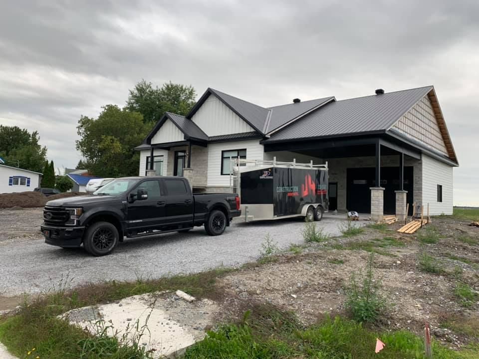 Un camion noir est garé devant une maison en construction.
